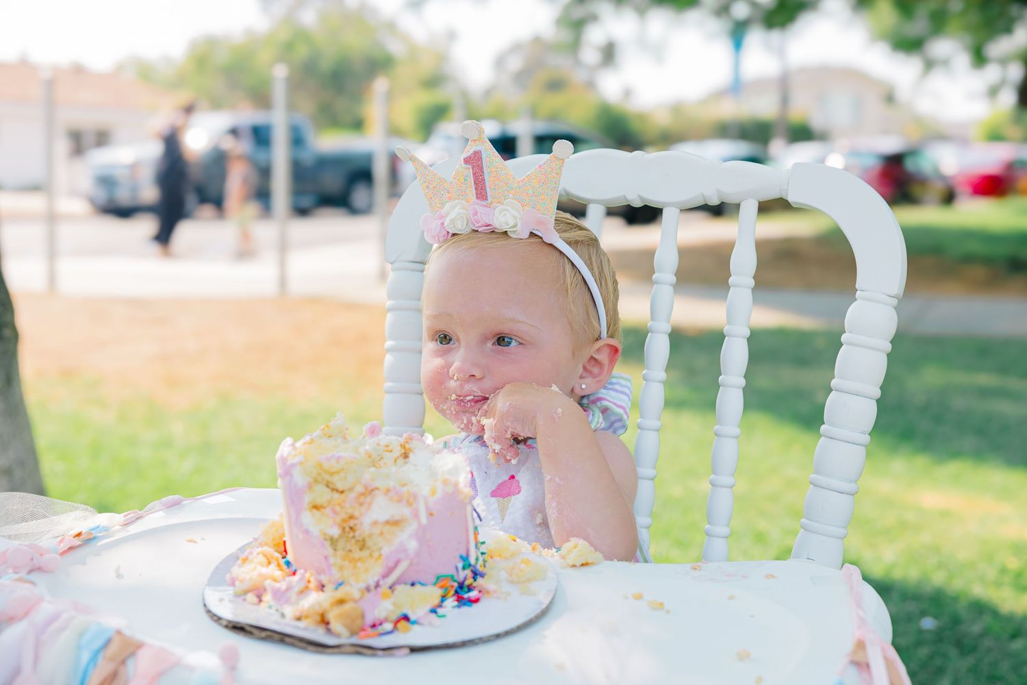 White birthday cake with sprinkles displayed on a decorated table at an outdoor party.