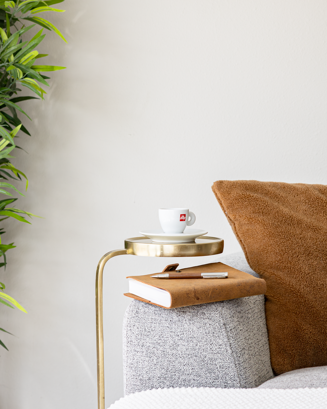 Cozy coffee corner with illy cup, brown pillow, and gold side table.