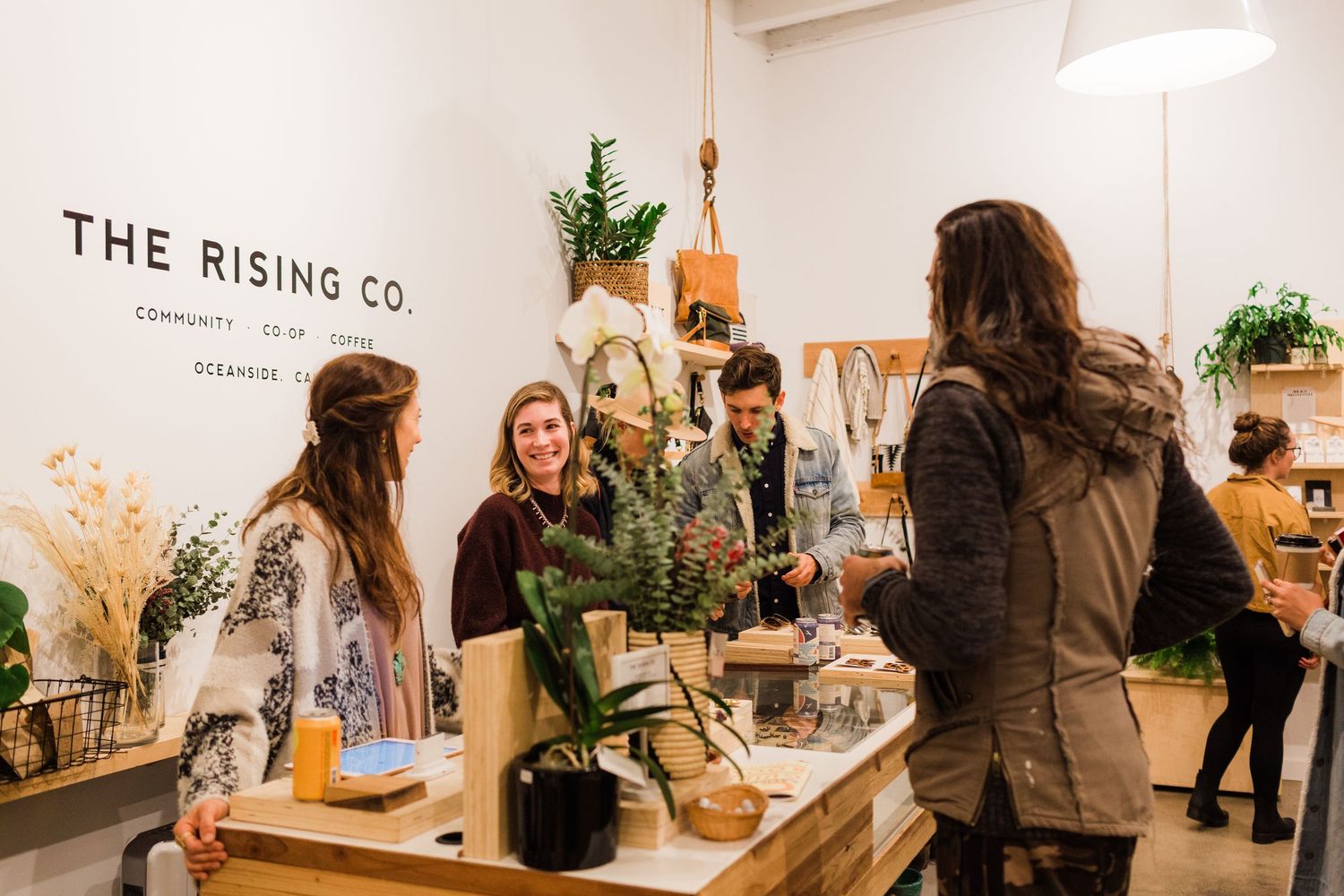 Interior of a stylish plant shop with customers browsing potted plants and decor in a bright retail space.
