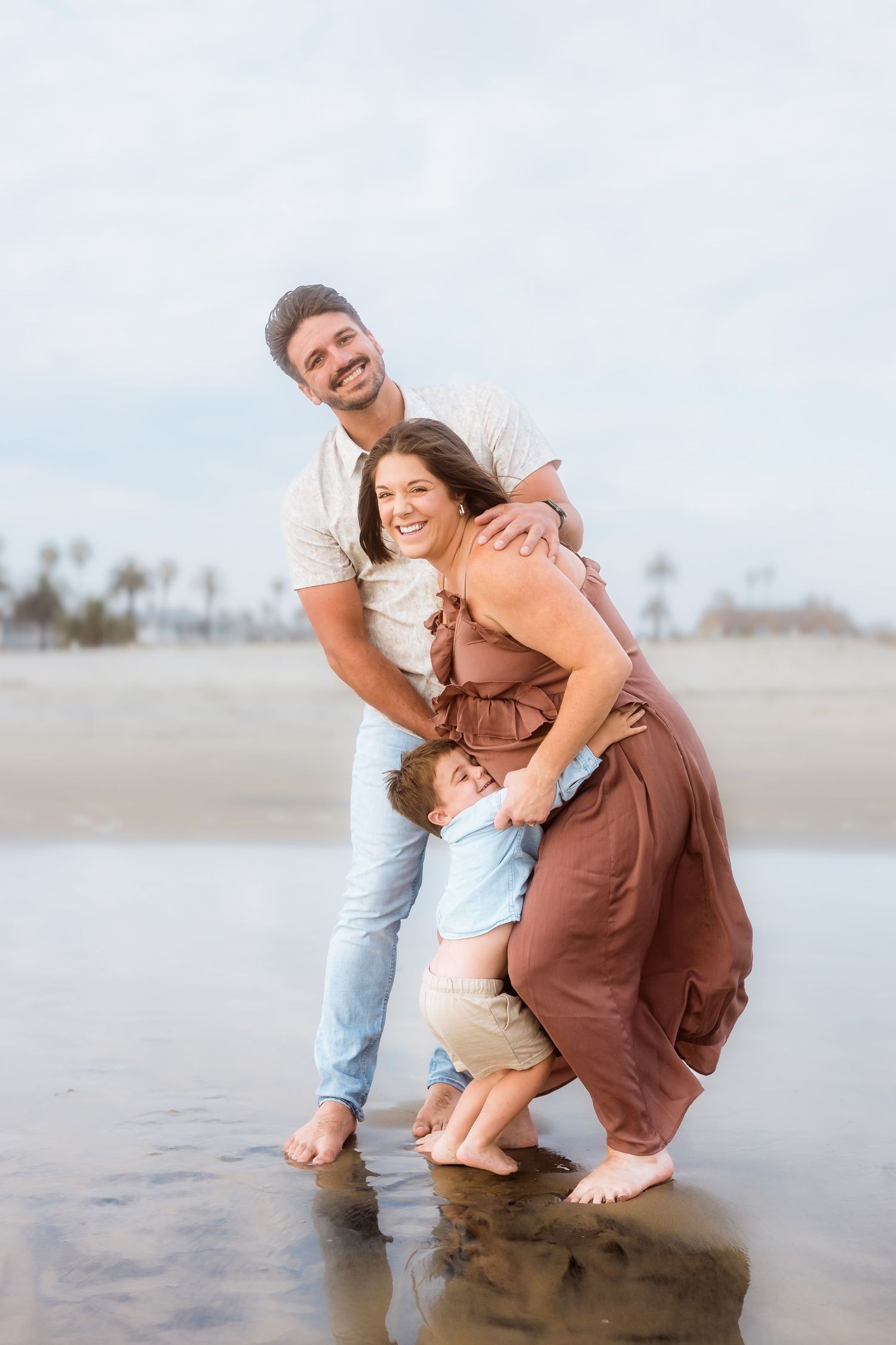 A family shares a tender moment together at the beach during sunset.