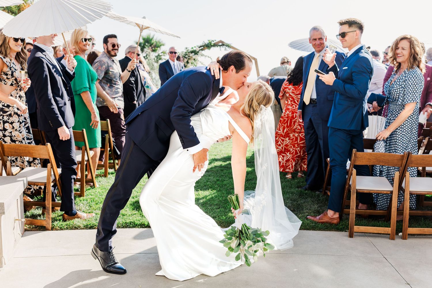 Wedding guests celebrate as newlyweds make grand exit under white tent reception.