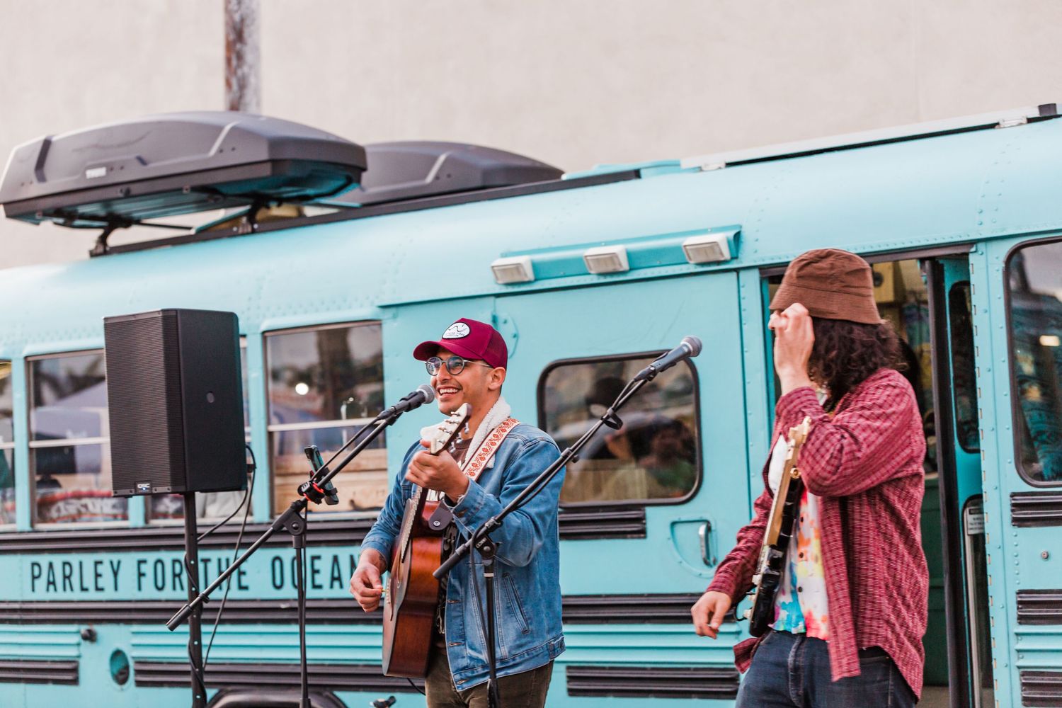 A line of hungry customers waiting outside a turquoise vintage food truck during lunch service.