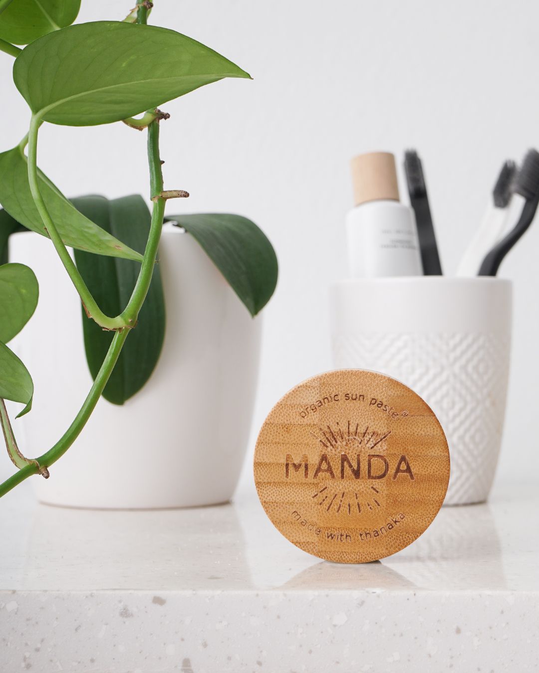 Wooden Manda compact displayed with houseplant and white organizational container.