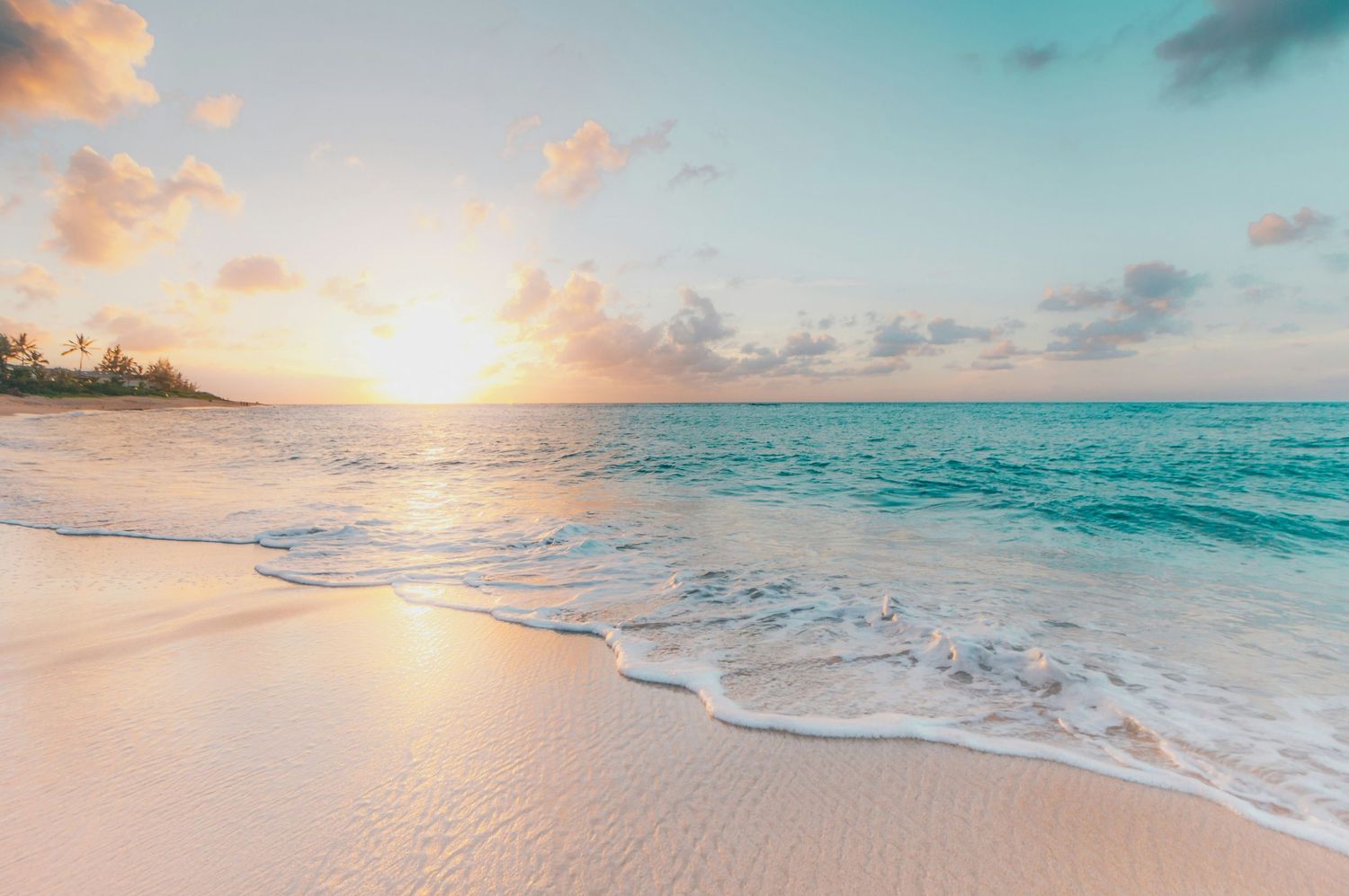 Stunning sunrise over turquoise ocean waves breaking on a pristine sandy beach.