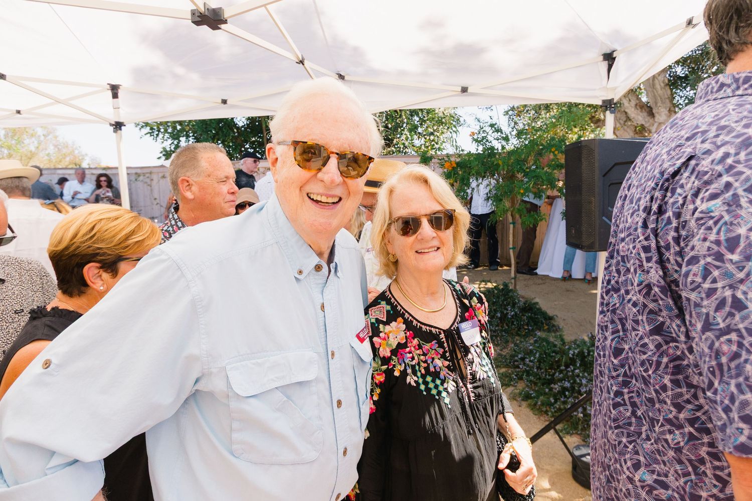 Guests enjoying themselves at a casual outdoor social gathering under white tents.