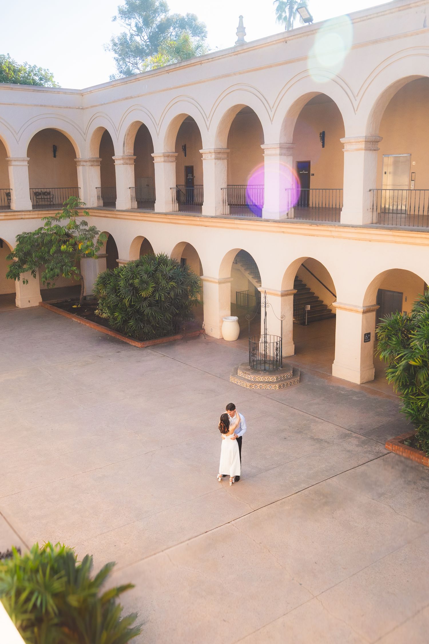 A couple shares a romantic moment in a Spanish colonial courtyard with beautiful arched architecture.