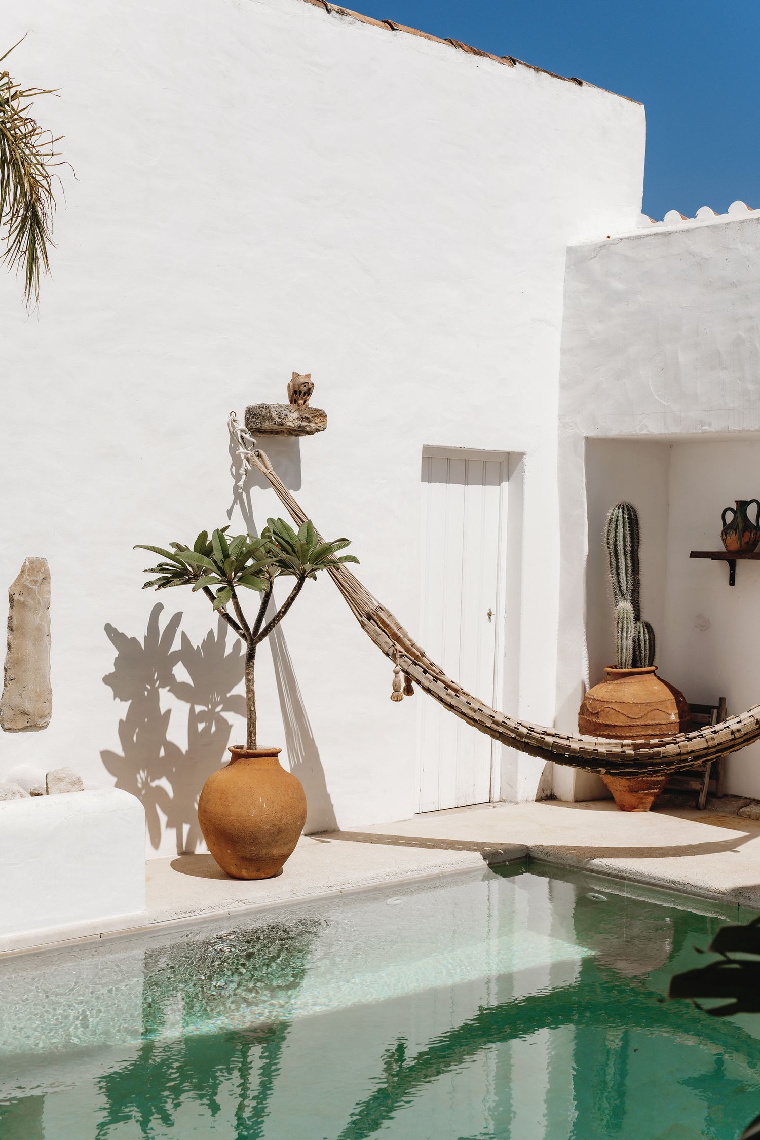 Modern white Mediterranean villa with turquoise pool and terracotta pots.