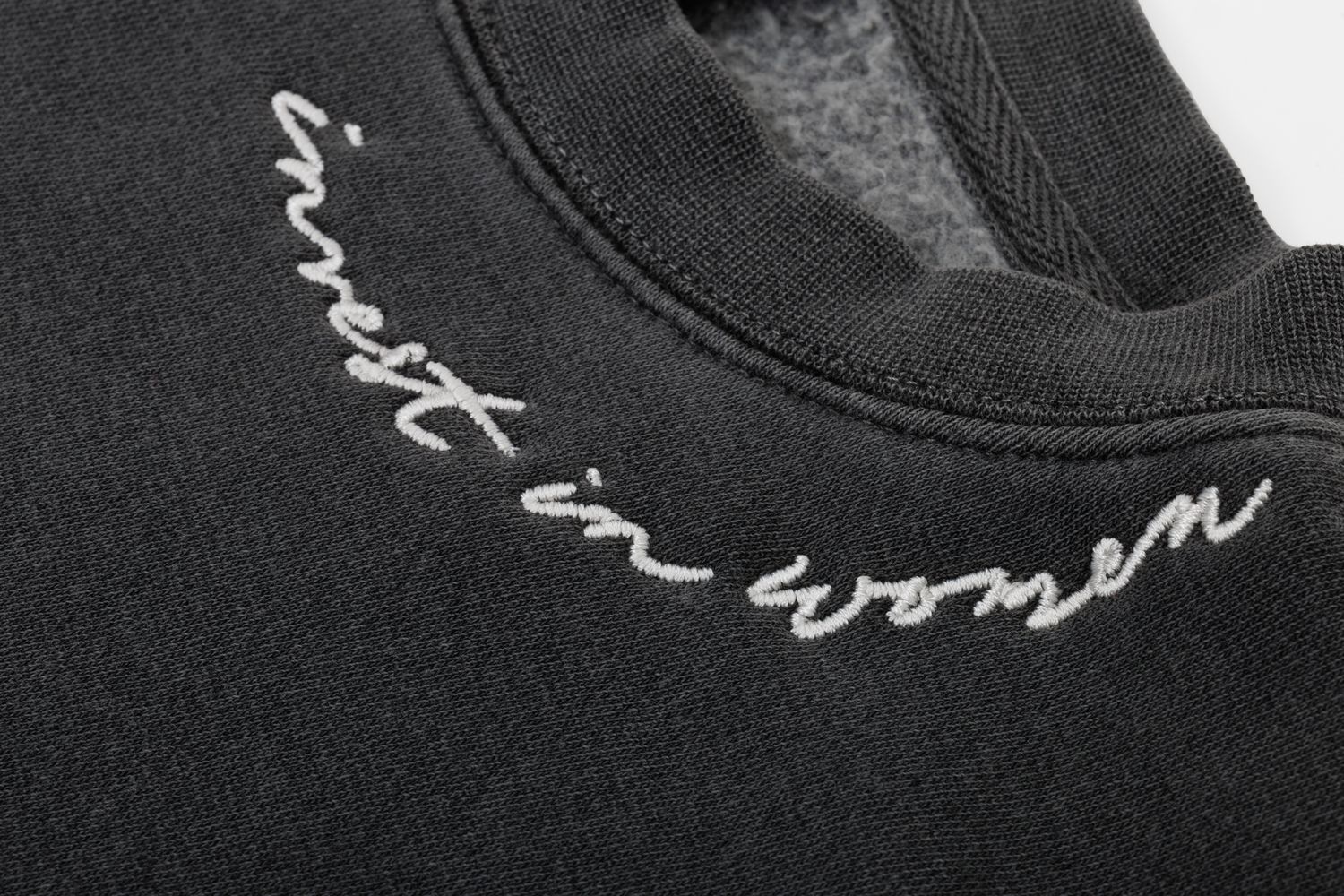 Close-up detail of cursive text embroidered on black fabric.