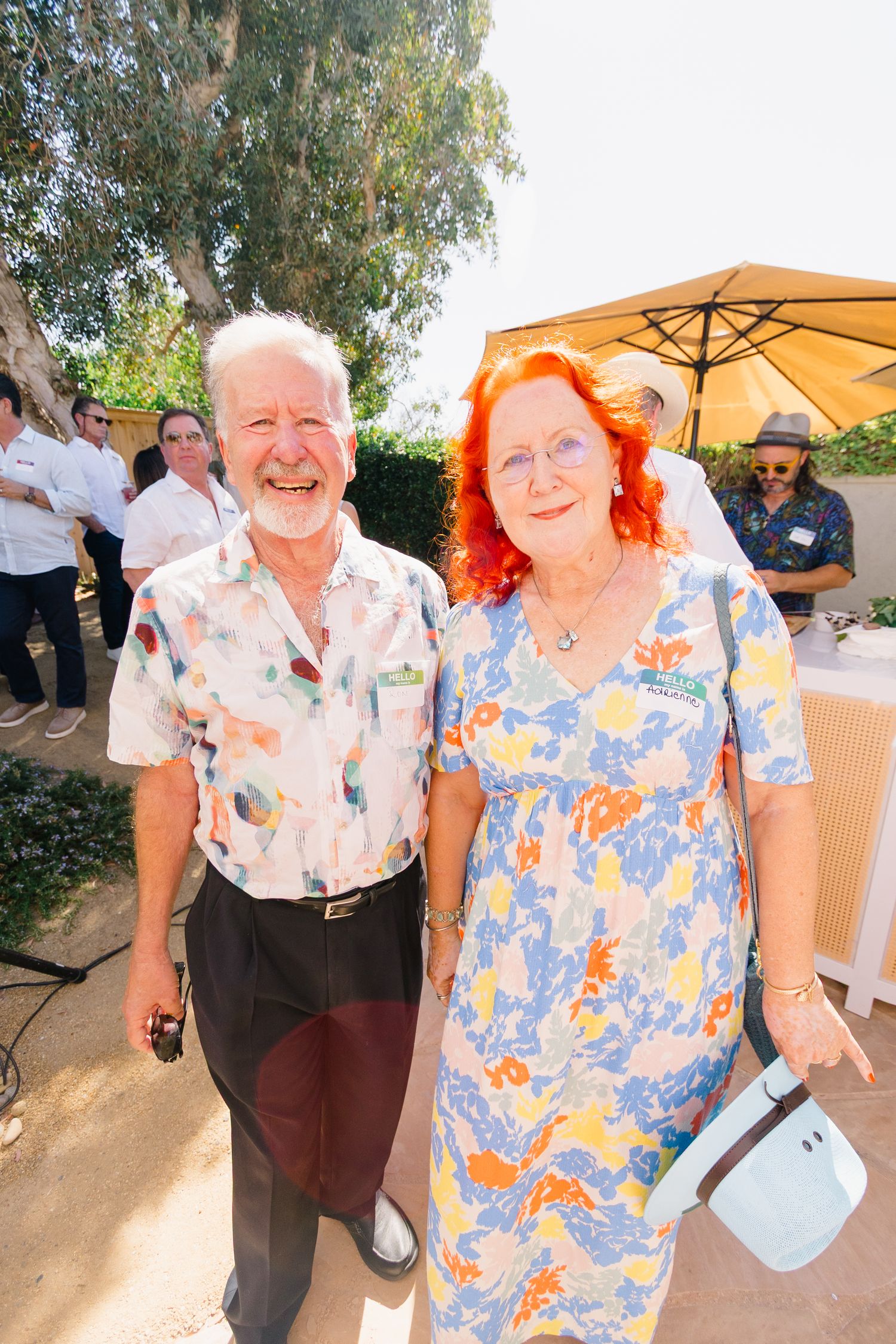 Guests enjoying a casual outdoor gathering wearing colorful floral shirts in a backyard setting.