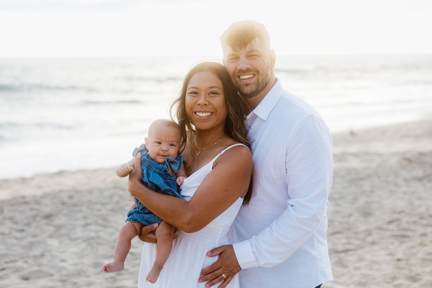 Family portrait session at the beach with soft lighting and ocean backdrop.