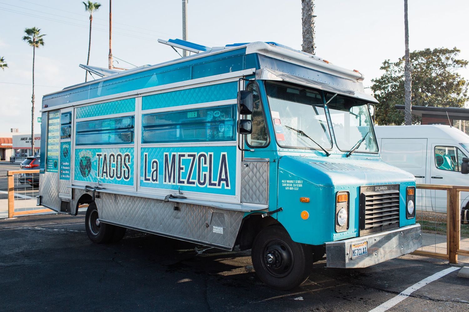 Row of classic turquoise food trucks with retro design parked in line showing different angles and perspectives.