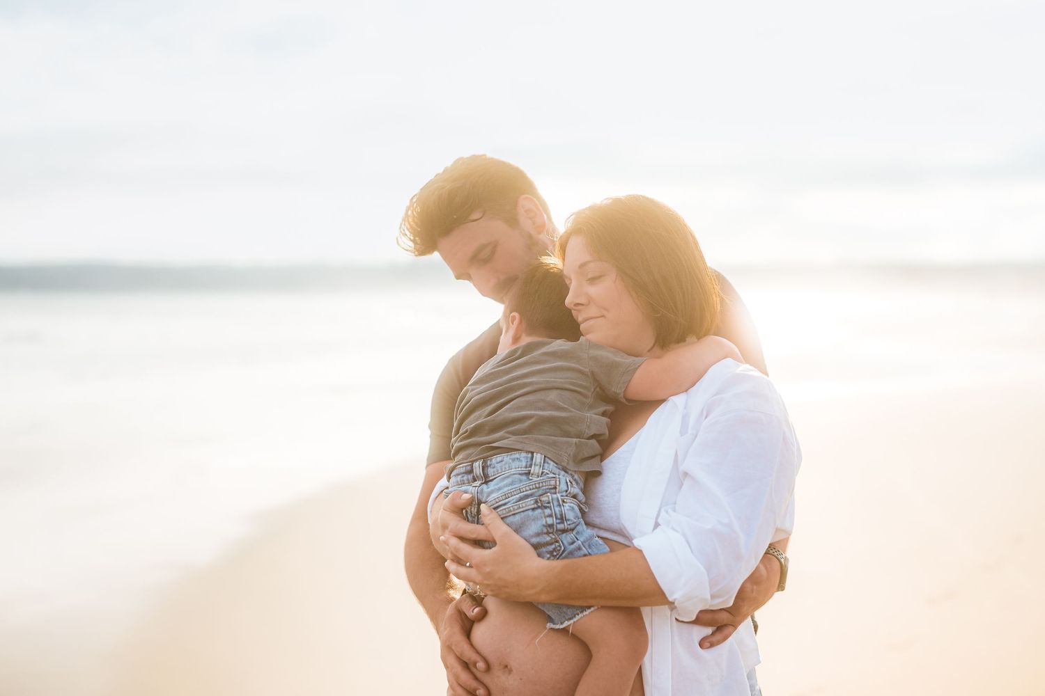 Romantic beach maternity photos showing sweet moments against a soft sunset backdrop.