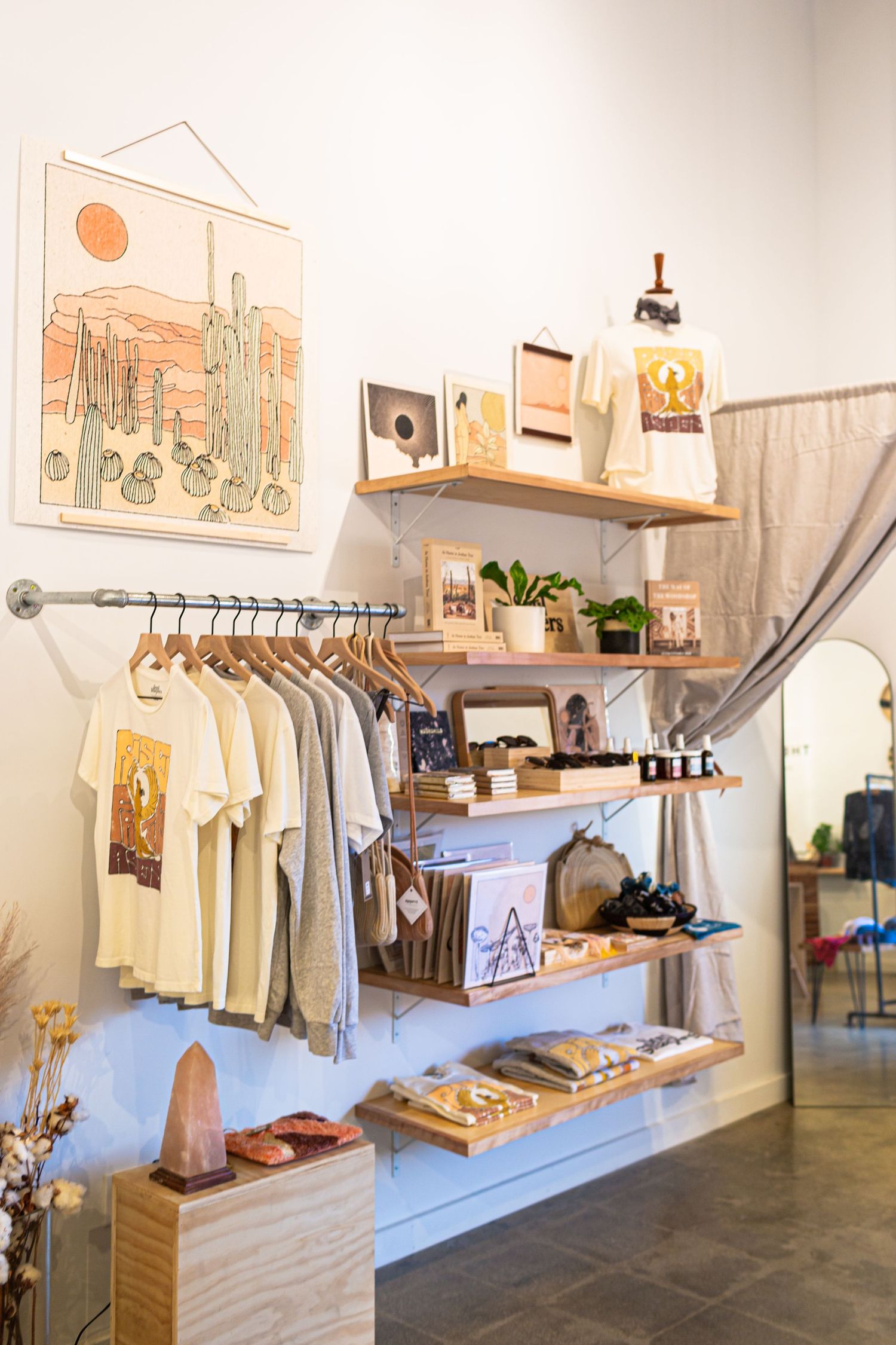Interior view of a modern boutique retail store showcasing minimalist clothing displays and wall art with natural lighting.