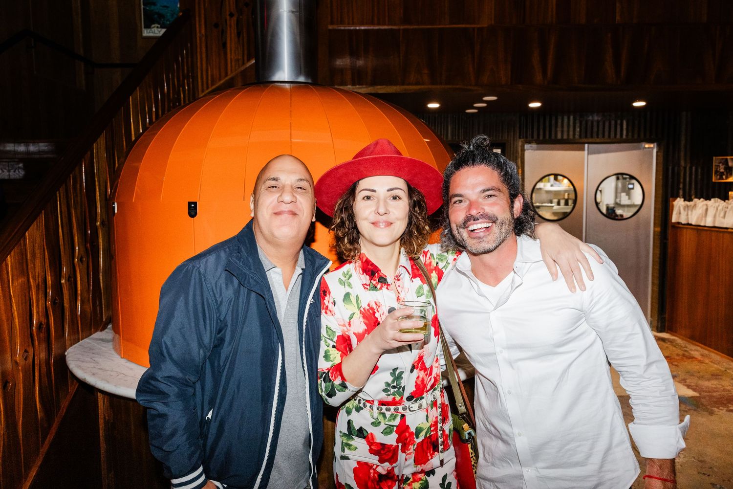 Restaurant staff posing in casual attire in front of a large orange pumpkin display.