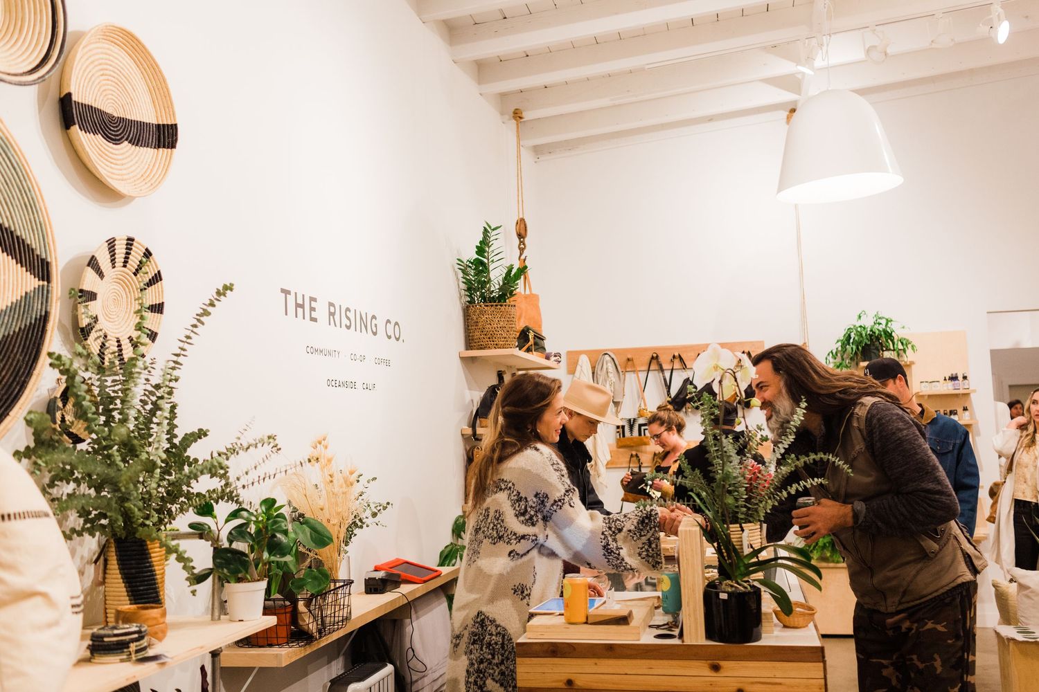 Interior view of a busy workshop space with plants, tables and crafting supplies in a bright white room.