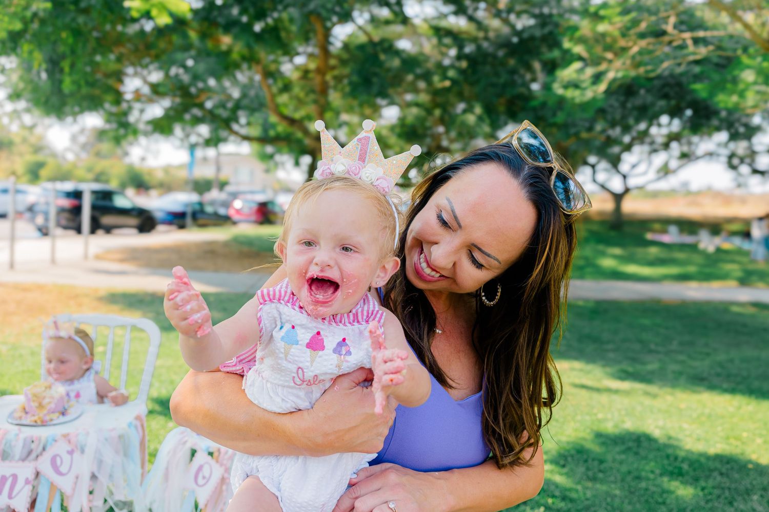 Mother and daughter having fun outdoors during a playful photo session with pink and purple decorations.