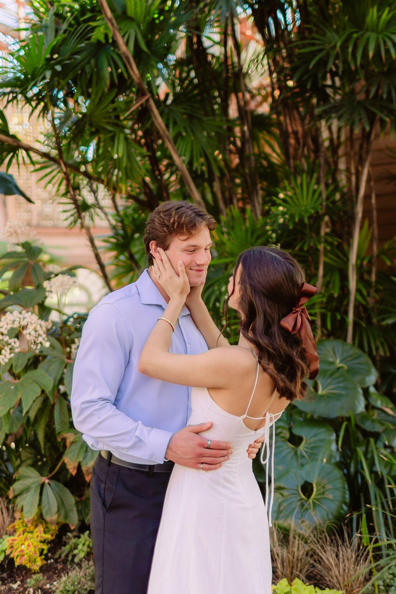 A tender moment shared between a couple surrounded by tropical plants and greenery.