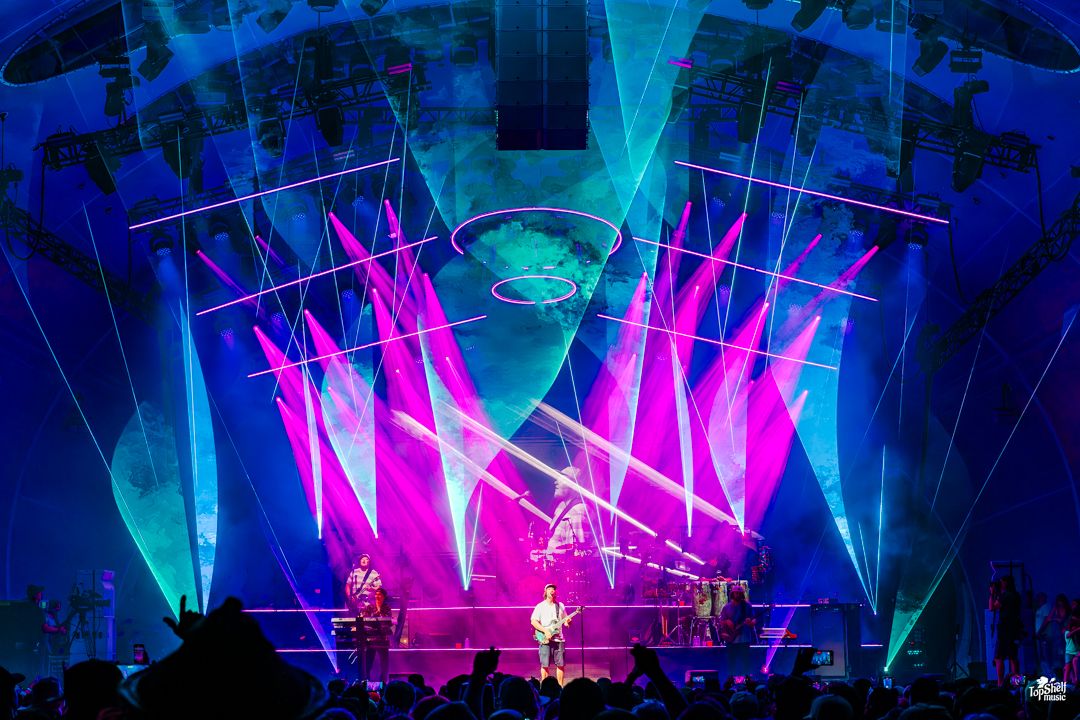 Concert stage lit with dramatic blue and pink lights creating a vibrant atmosphere during a live performance.