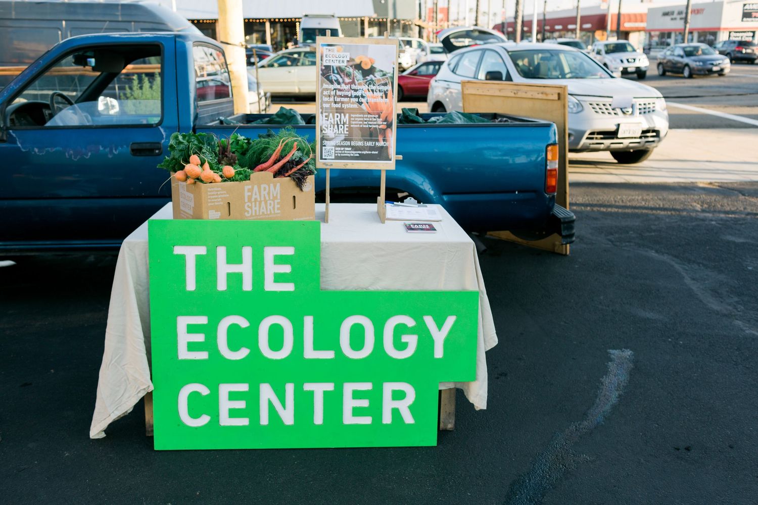 Six bright green signs in a parking lot display parts of text that appear to form a longer message.