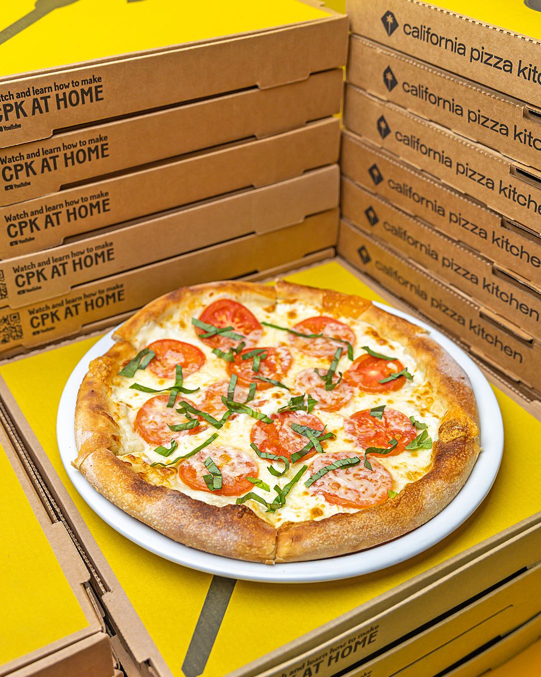Fresh California Pizza Kitchen pizzas displayed on yellow background.