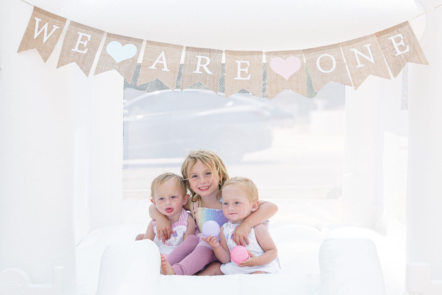 A baby gender reveal pregnancy announcement banner spells out 'We Are On A' in pink and gold paper decorations.