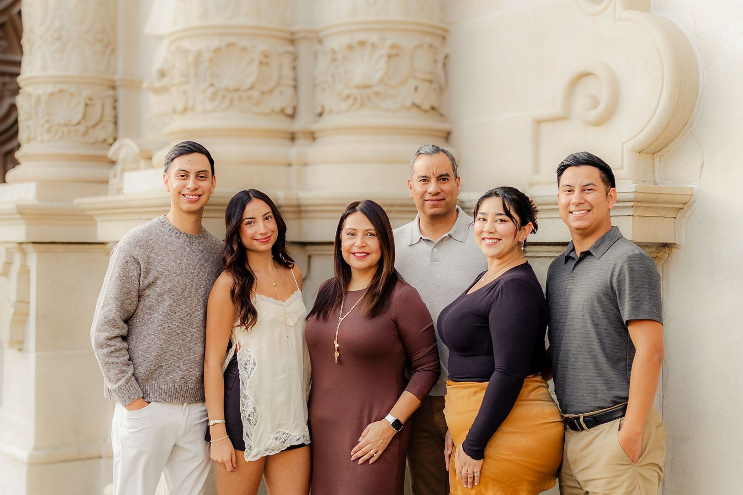 A group poses together in front of ornate white stone architecture with decorative columns and arches.