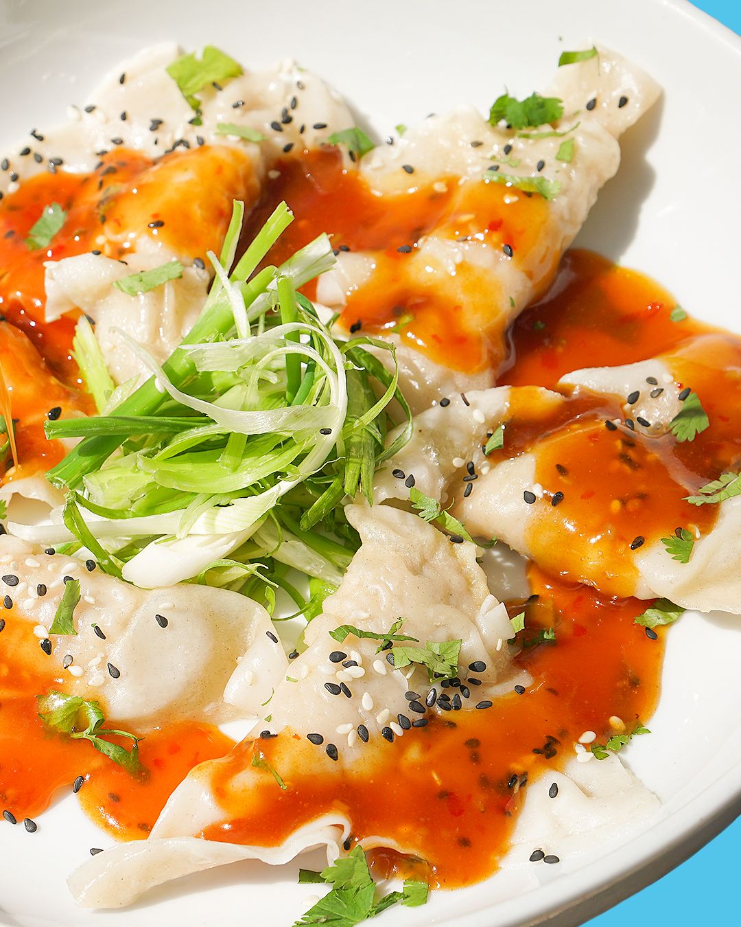 Sushi rolls garnished with microgreens and spicy sauce on white plate.