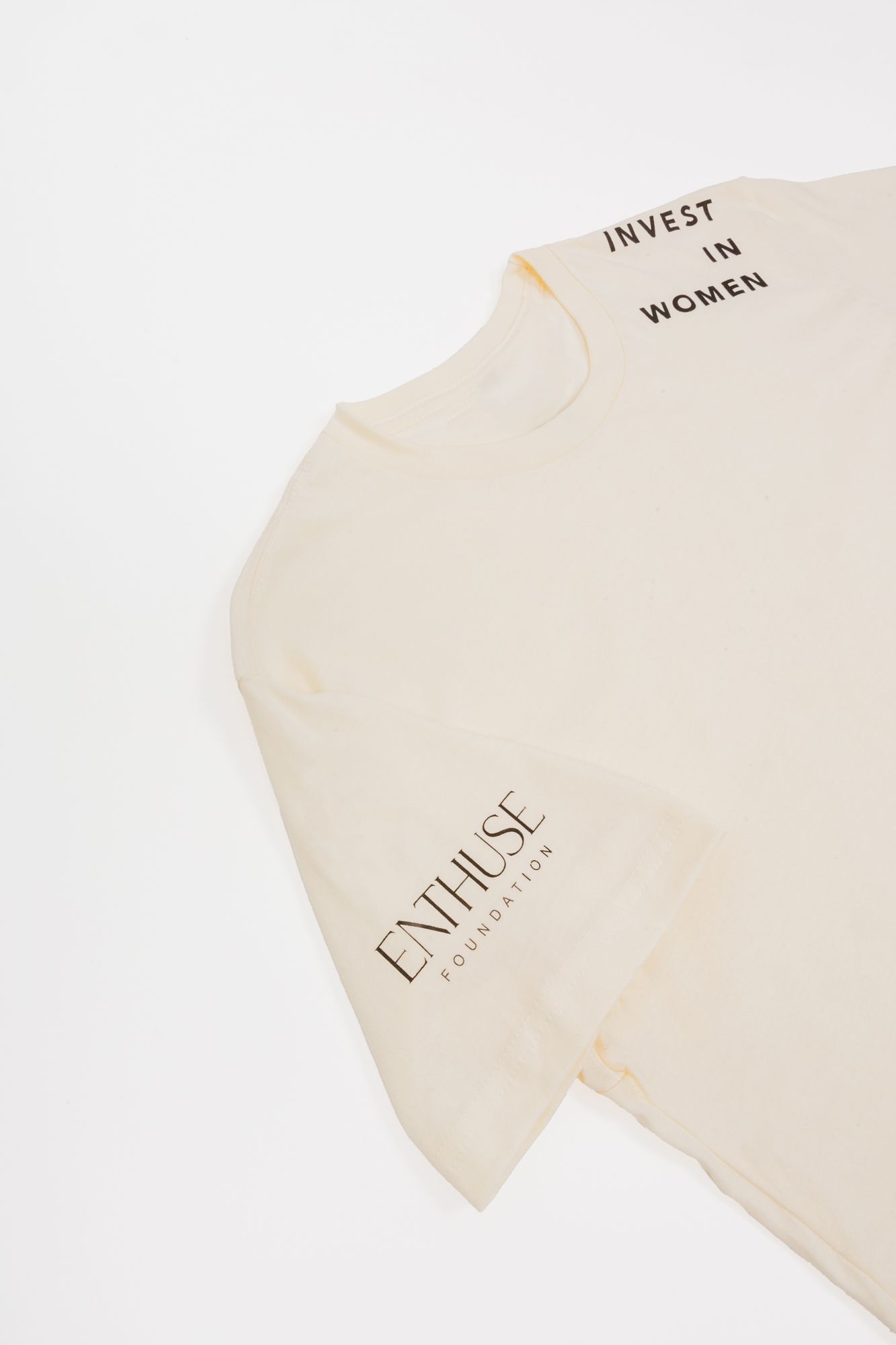 Cream-colored t-shirt with 'INVEST IN WOMEN' text and Enthuse Foundation branding.