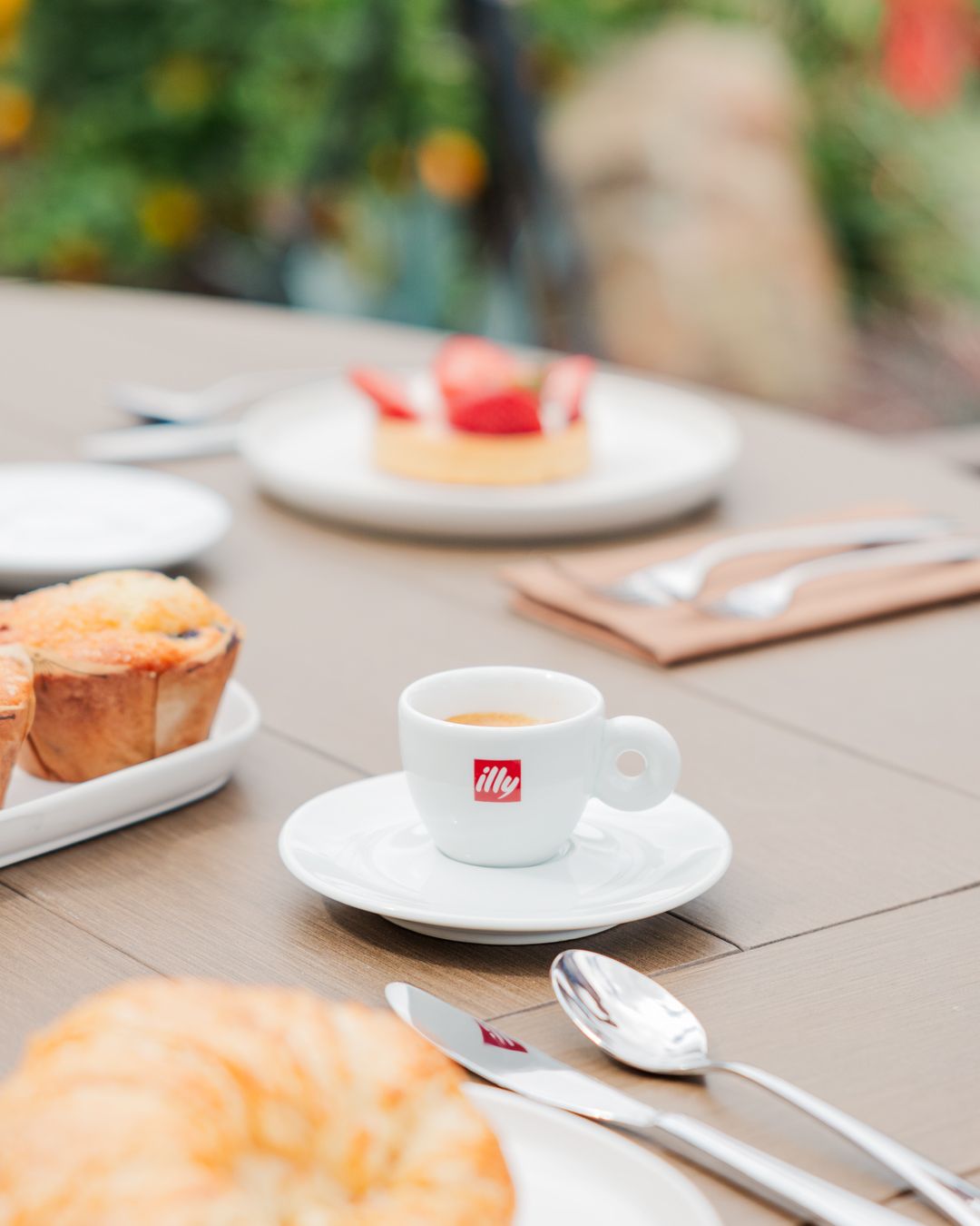 Breakfast table setting with illy espresso cup, pastries and cutlery.