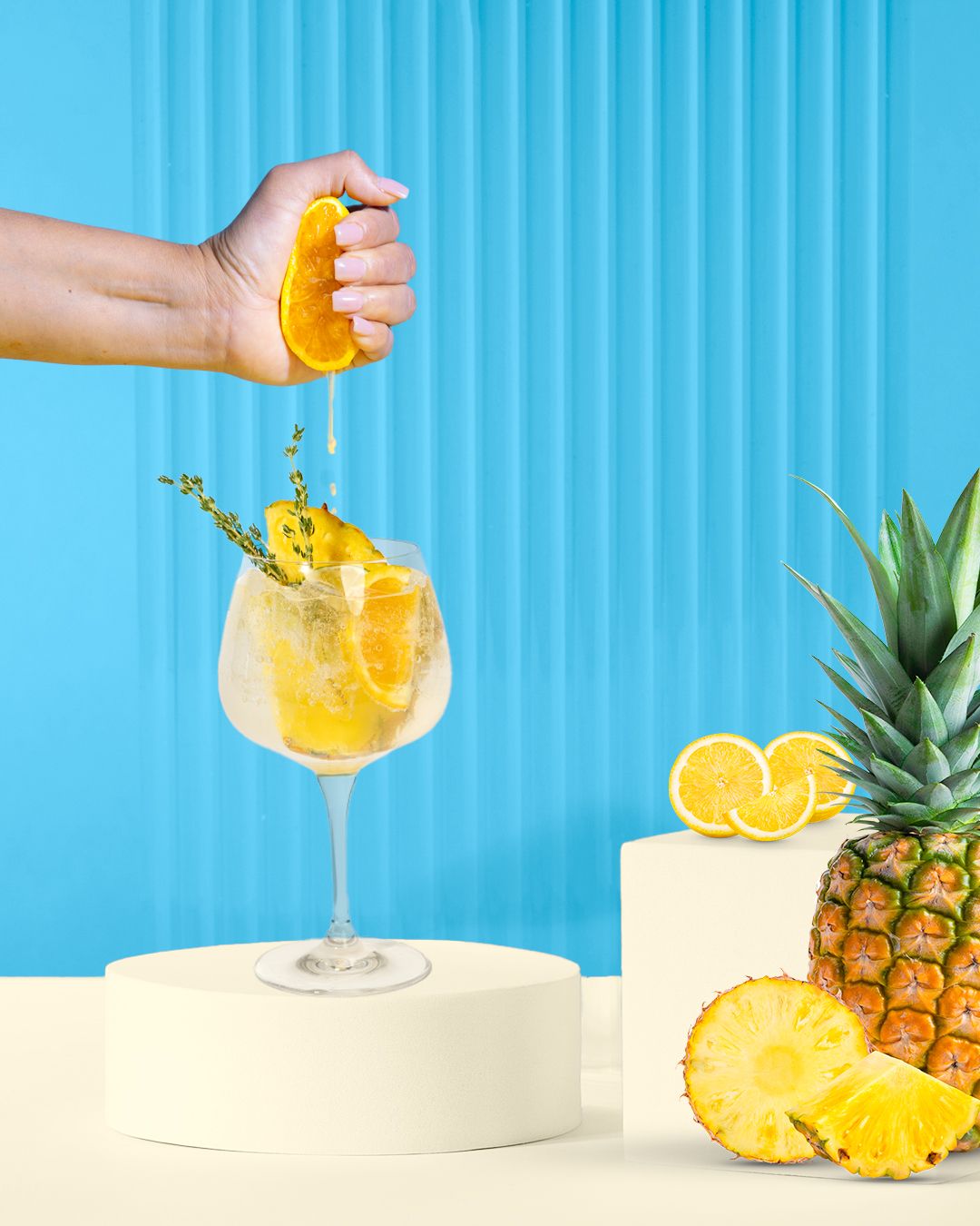 Tropical pineapple cocktail being poured into a glass with a bright blue background.