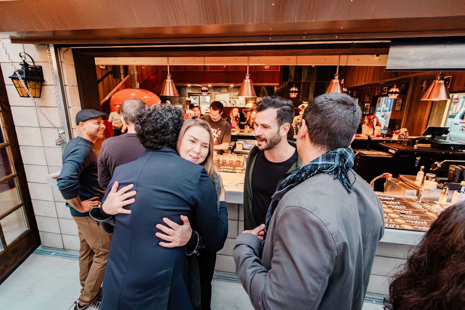 People gather and socialize at a cozy restaurant with warm lighting and rustic wooden accents.