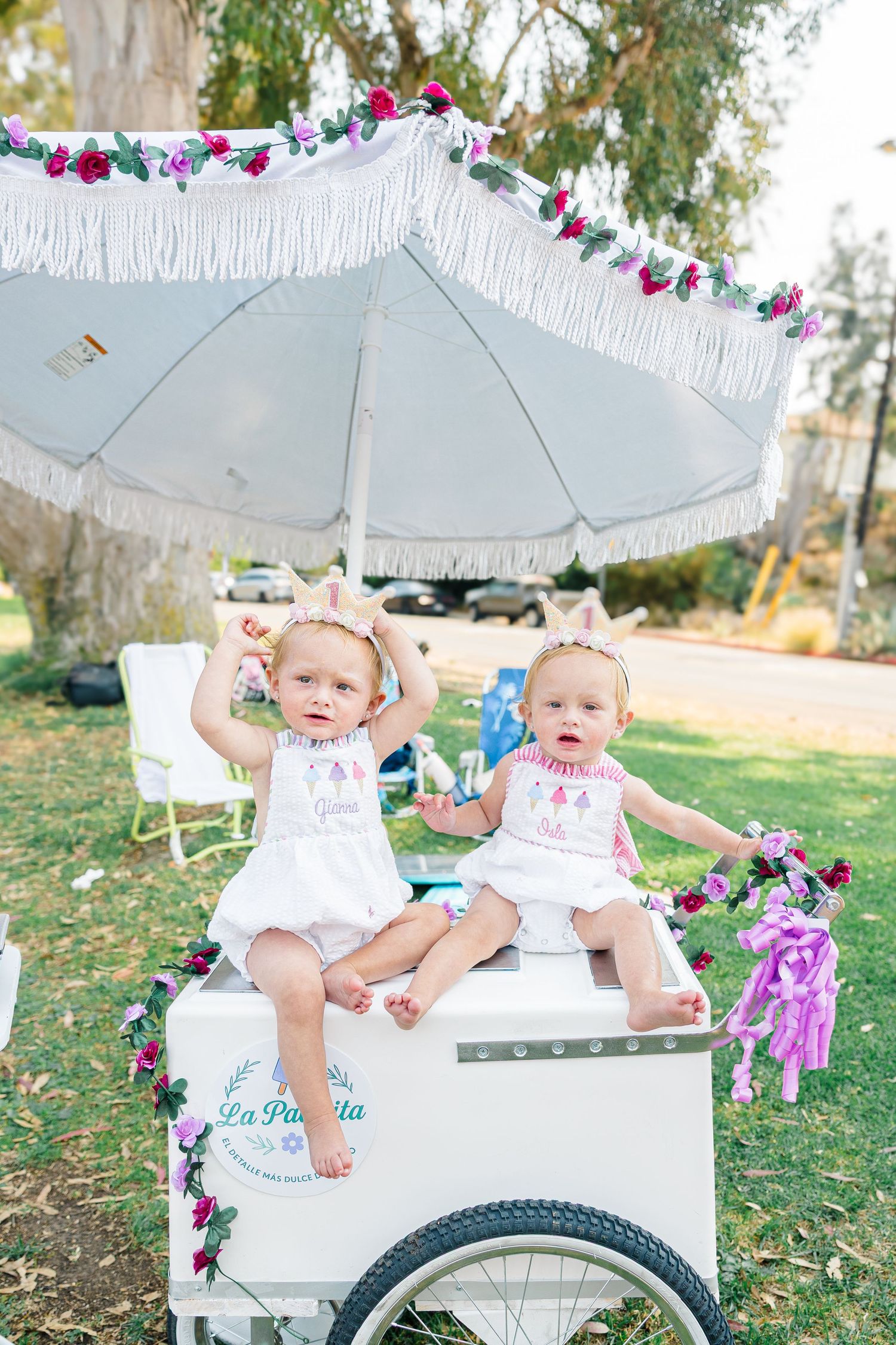 Outdoor party setup with white carriage and floral decorations in a garden setting.