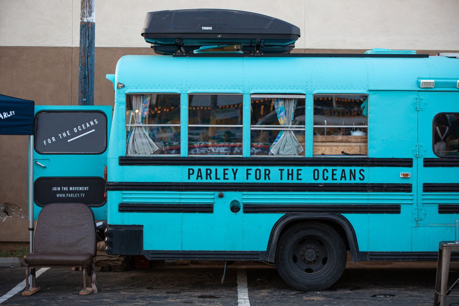 Series of blue vintage buses parked in line featuring 'Padlets For The Oceans' text on their sides.