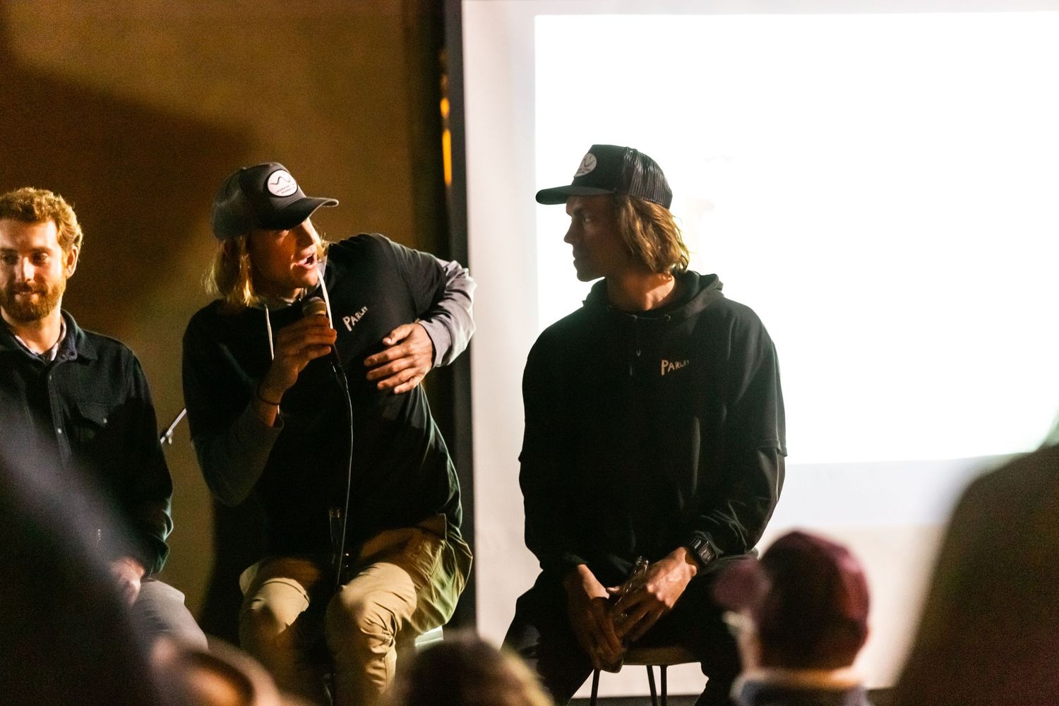 People gather in what appears to be a dimly lit recording studio or performance space.