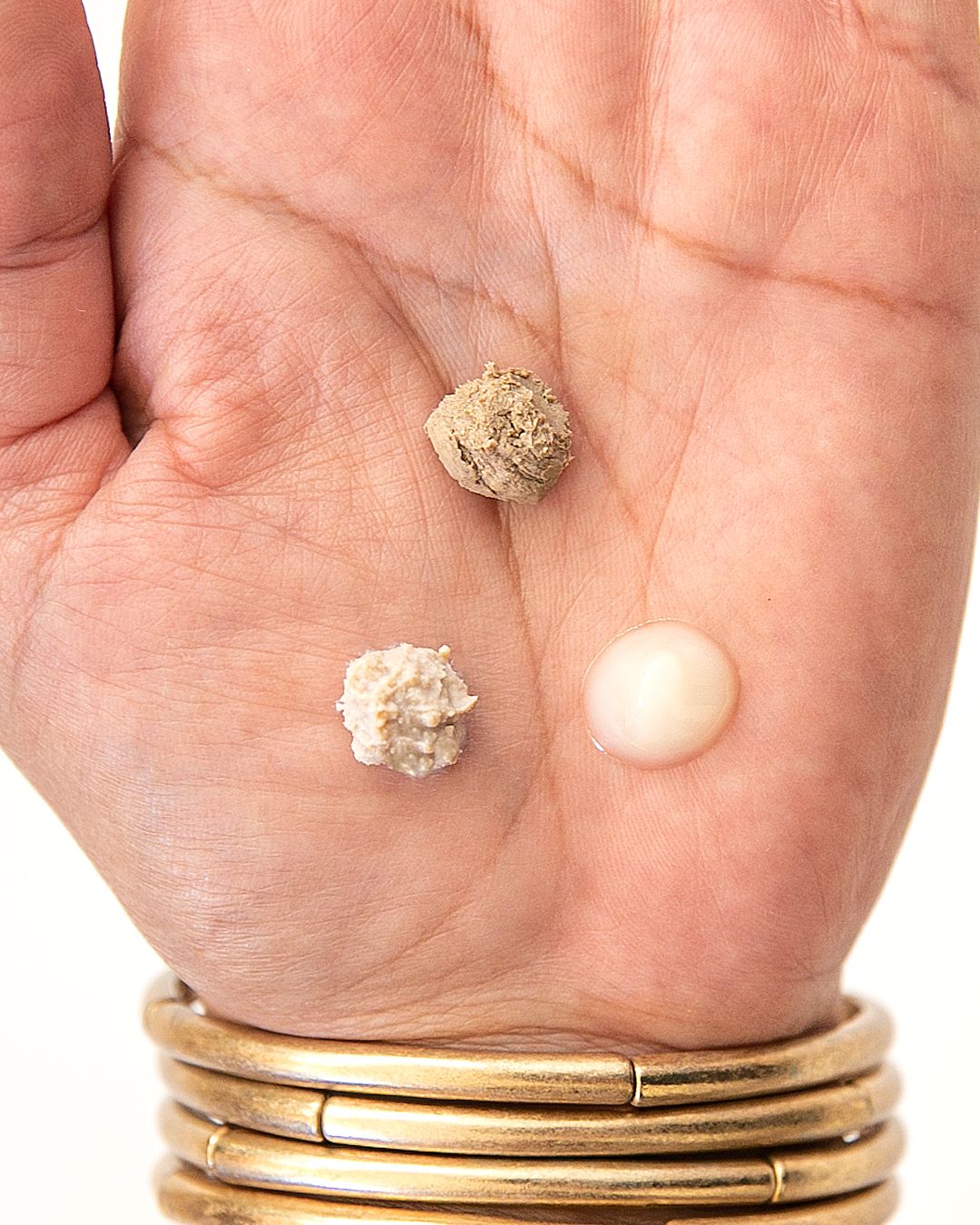 Close-up of hand holding small samples of natural skincare product ingredients.