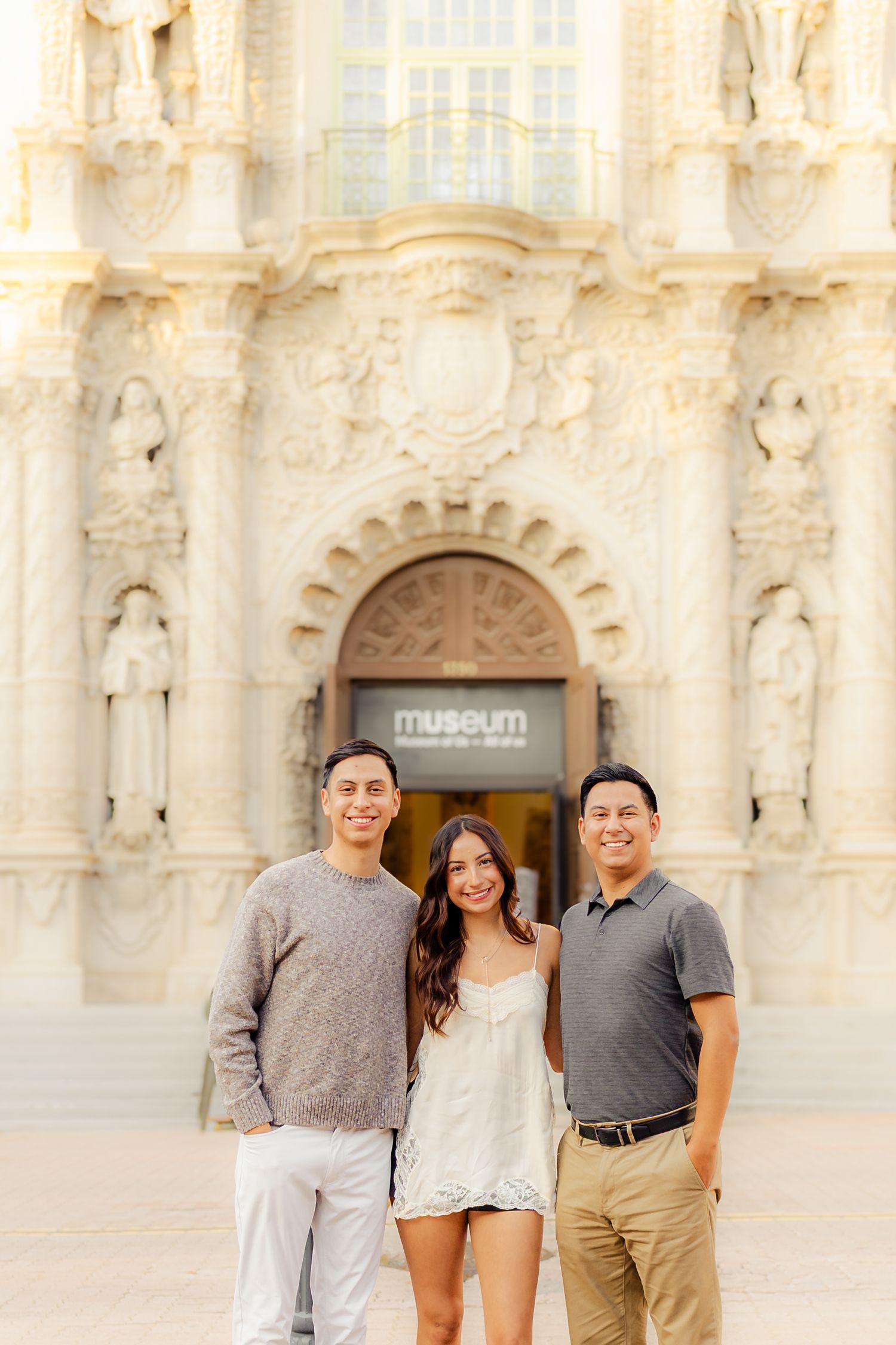 Group poses for photos in front of historic Mission San Luis Rey church facade in Oceanside, California.