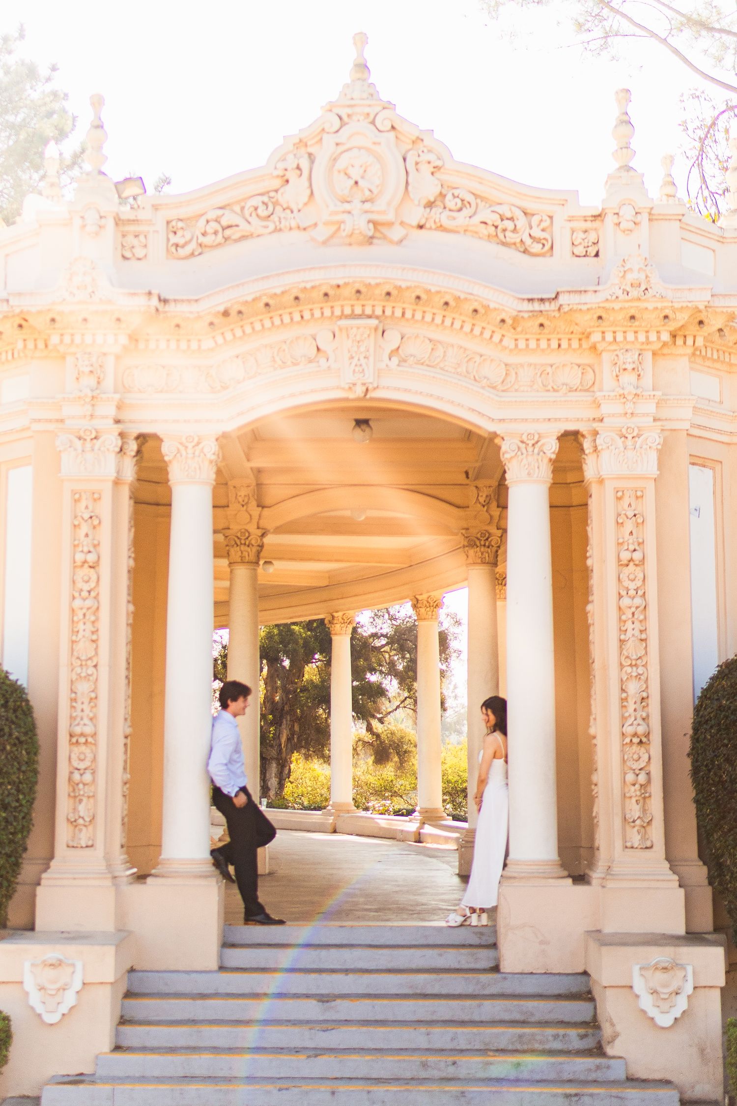 Ornate white colonnade with decorative archways and steps in a Mediterranean architectural style.