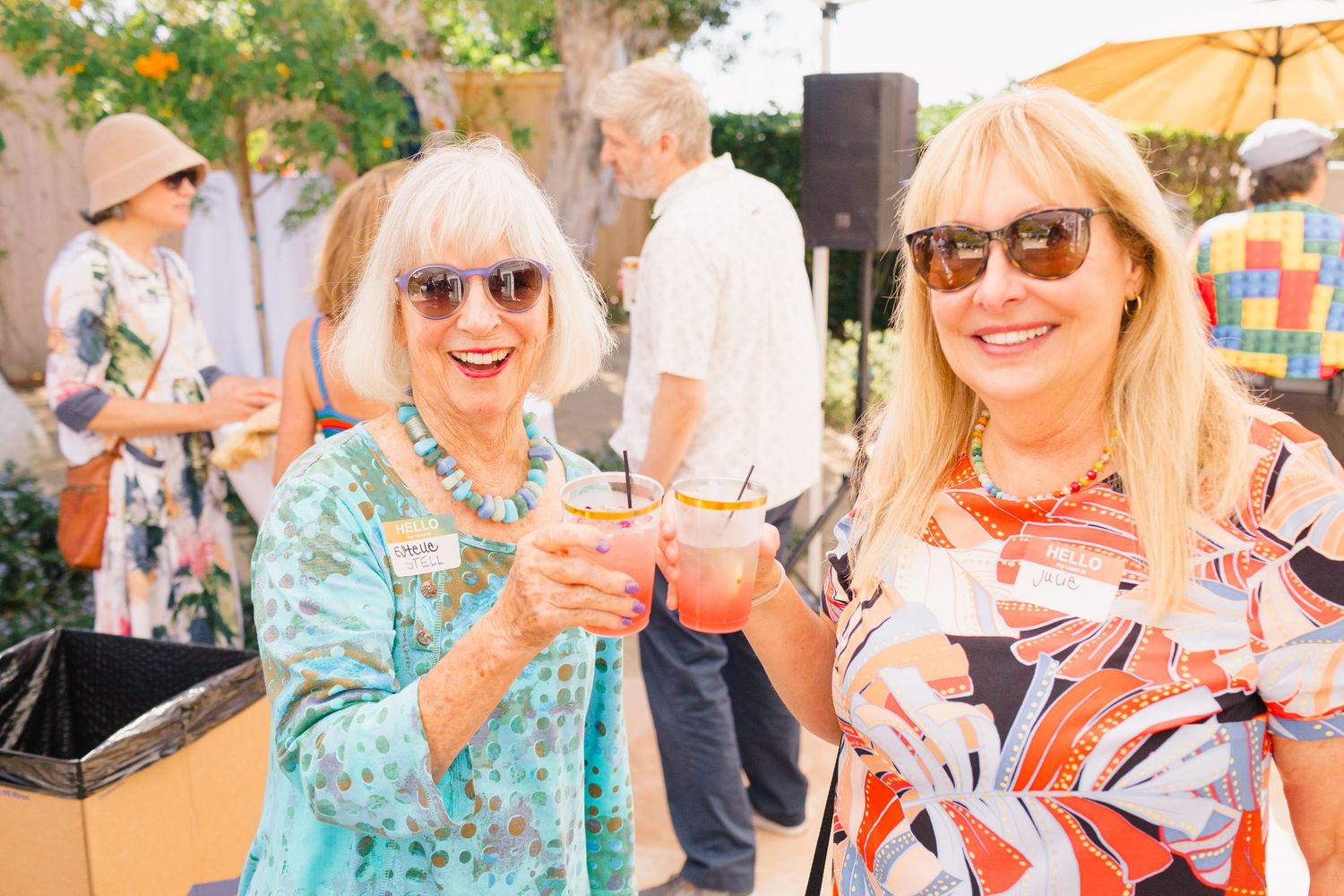 People enjoying a sunny outdoor gathering with drinks and smiles at a social event.