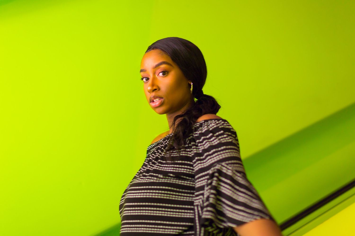 Portrait session against a bright lime green background with dramatic lighting.