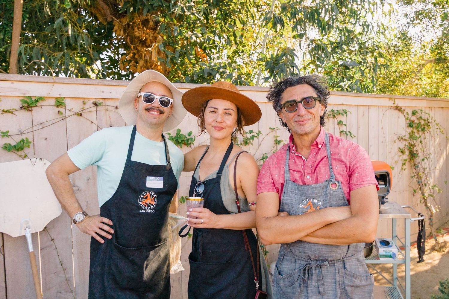 Garden party attendees posing together under trees at a summer social gathering.