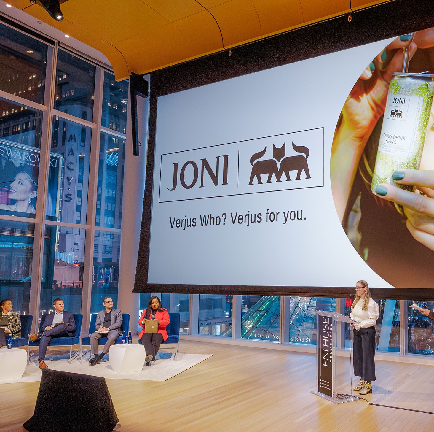 Stage presentation featuring a large Joni logo with two black cat silhouettes and brand slogan display on white screen.