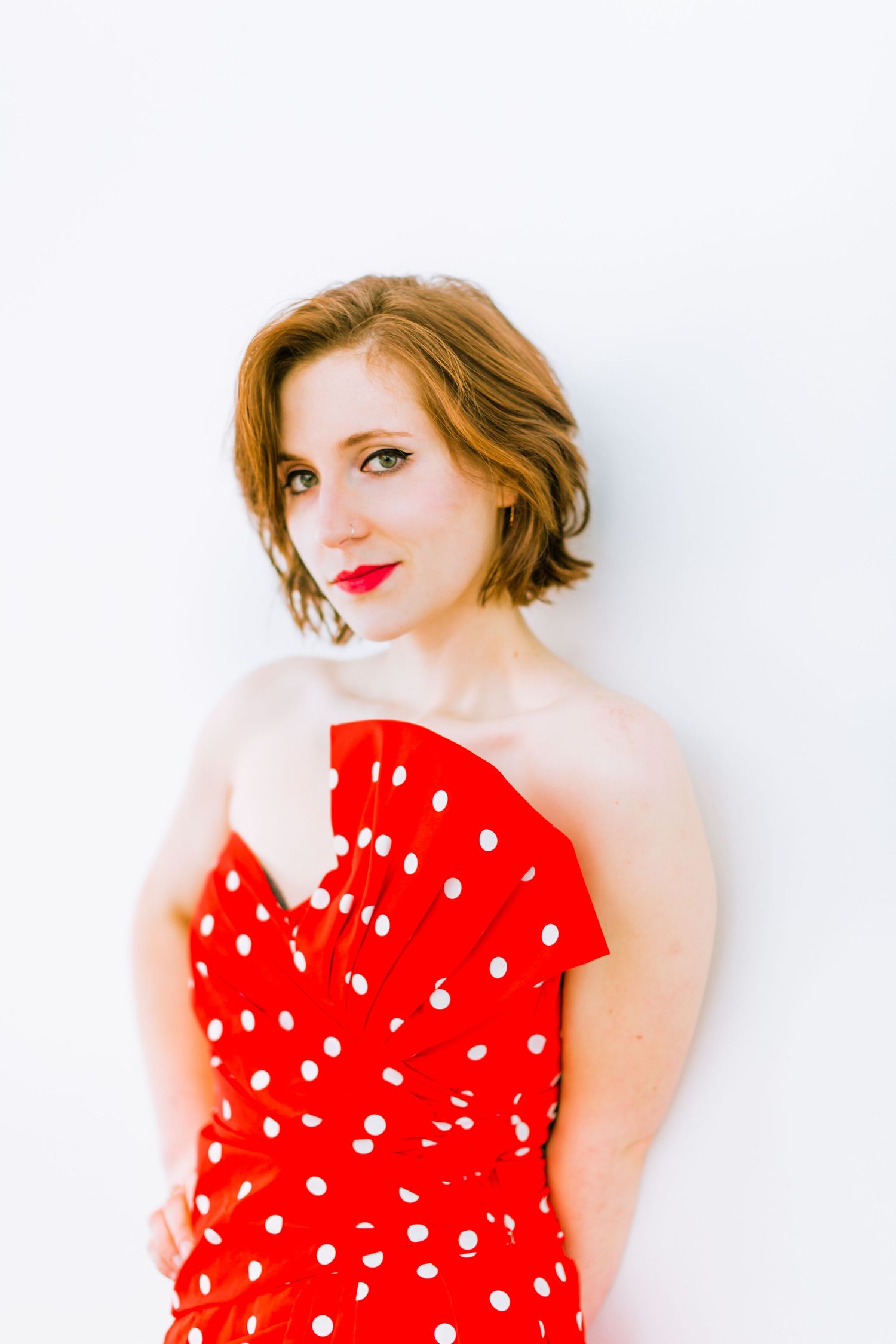 A retro-inspired portrait featuring a polka dot red dress against a white background.