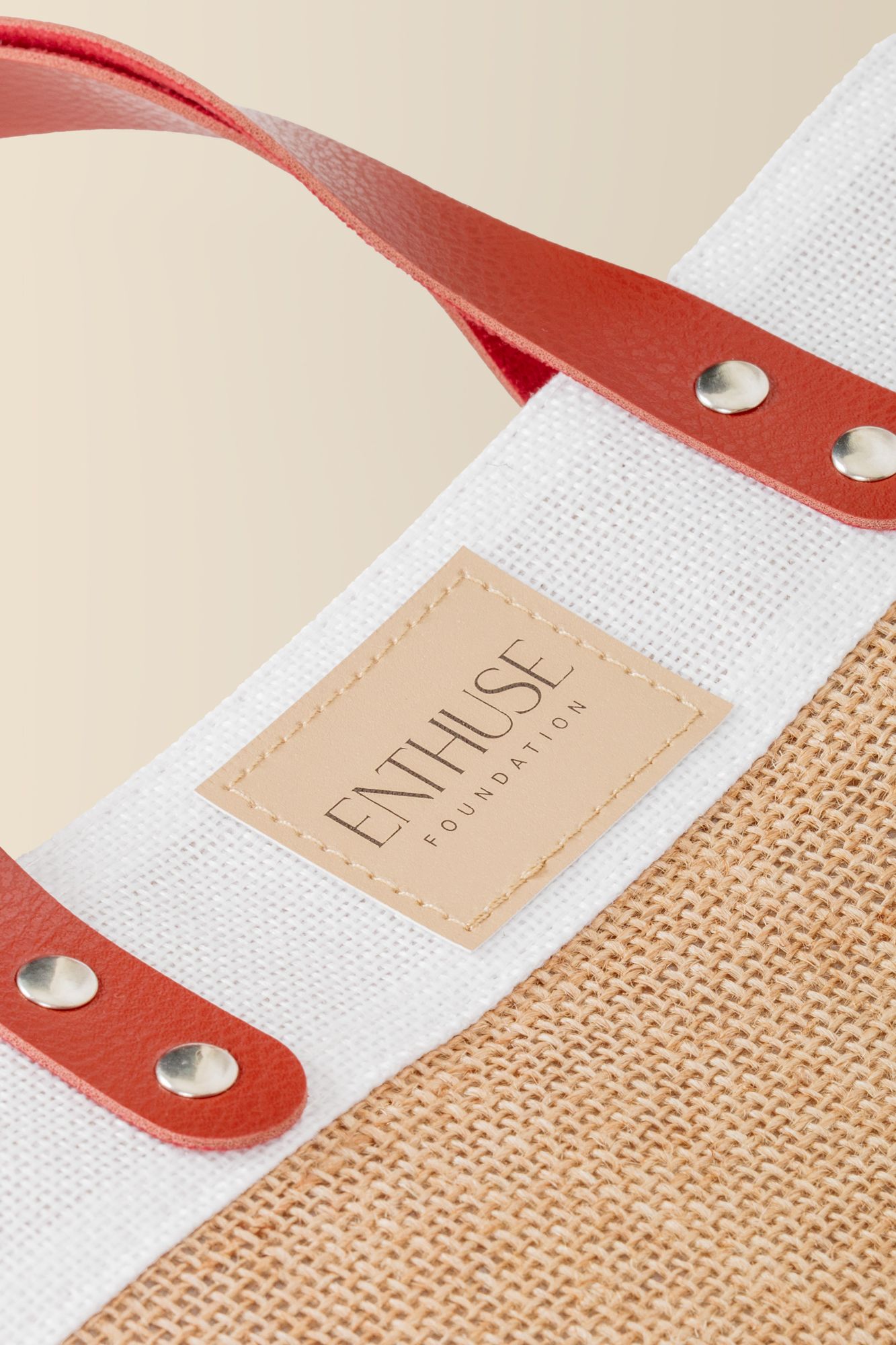 Close-up of canvas and burlap tote bag showing leather handle attachments and branding.