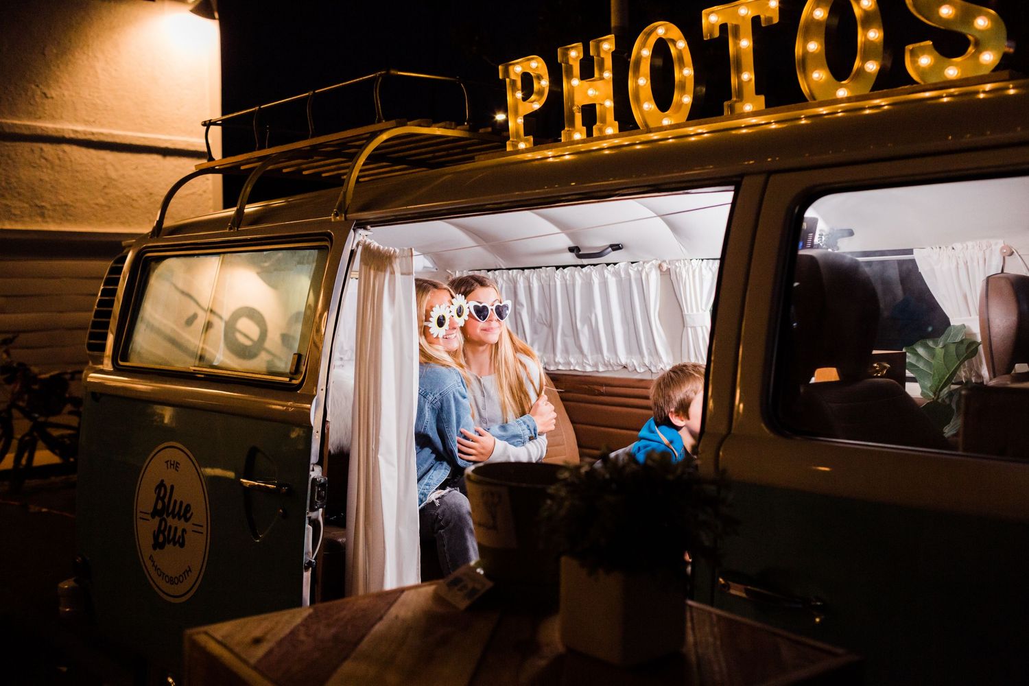 Photos store front window decor displaying vintage camera equipment and signs on wooden shelving at night.