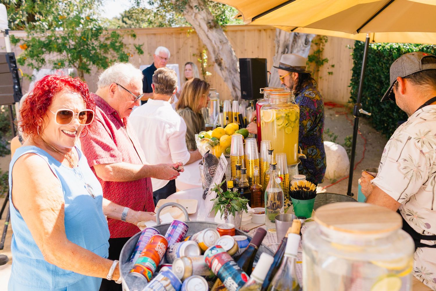 Guests mingling and enjoying beverages at a sunny outdoor party.