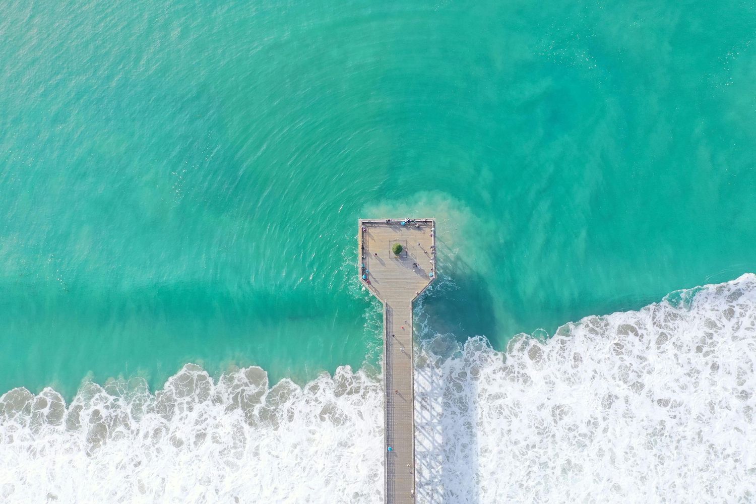 Aerial view of turquoise ocean waves crashing onto white sandy beach.