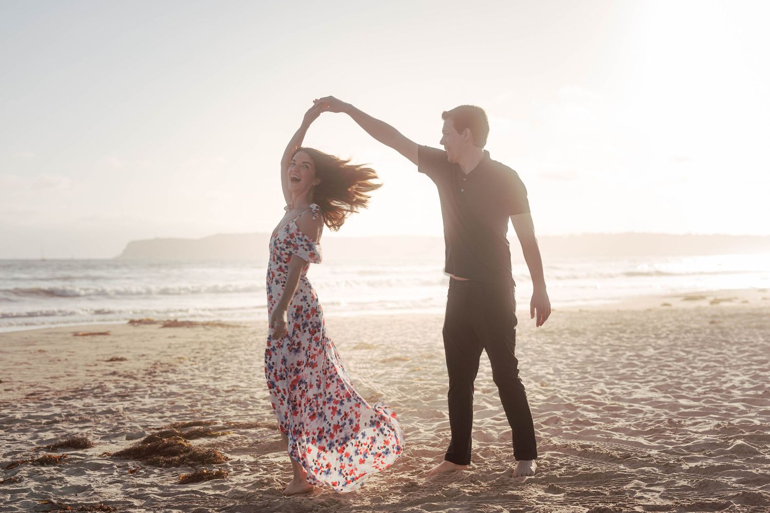 Playful couple walking and dancing together on beach during golden hour.