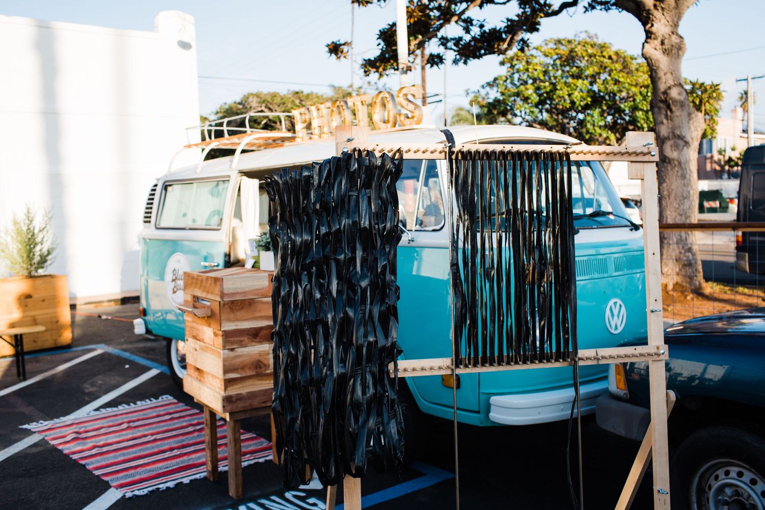 Mobile surfboard rental truck with black bamboo curtains parked by the beach on a sunny day.