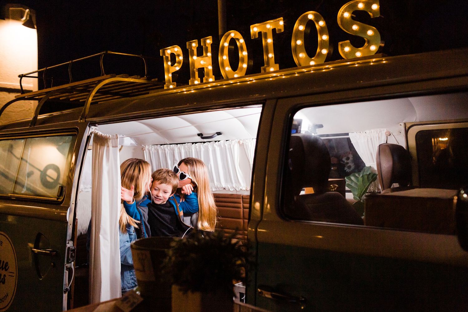 Illuminated yellow letters spelling 'PHOTOS' glow warmly on a dark storefront at night.