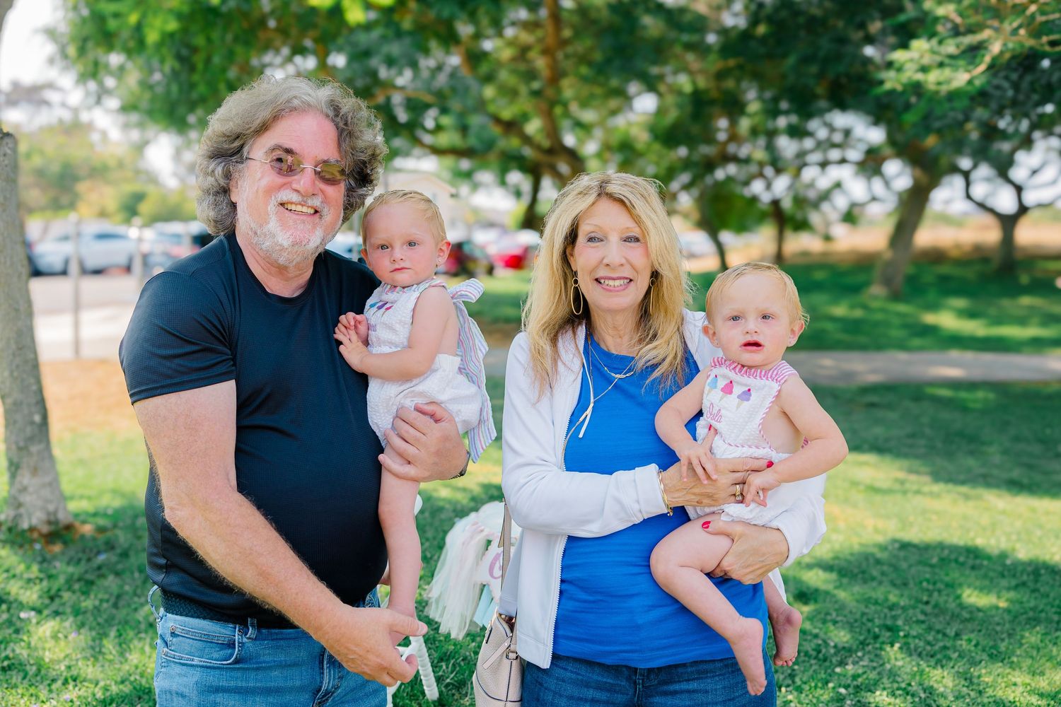 Family enjoying a summer outdoor photoshoot together in a grassy park setting.